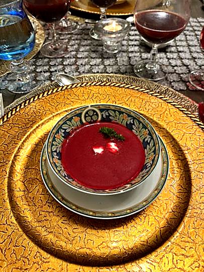 A deep red beet soup swirled with cream and topped with a herb sprig.