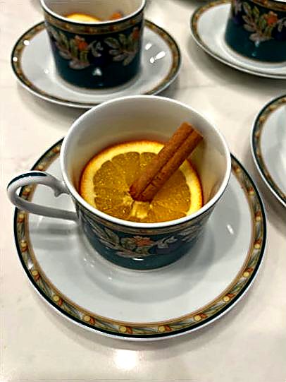 A teacup of honey rakia with an orange slice and a cinnamon stick.